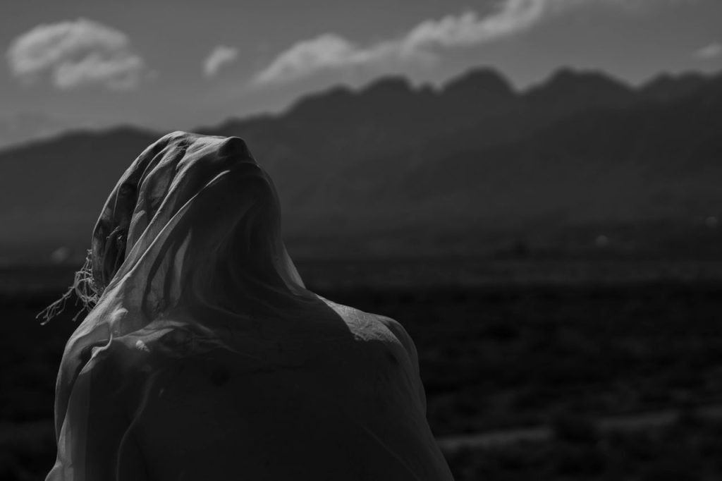 Silhouette of a person draped in cloth with a mountainous background, offering a moody vibe.